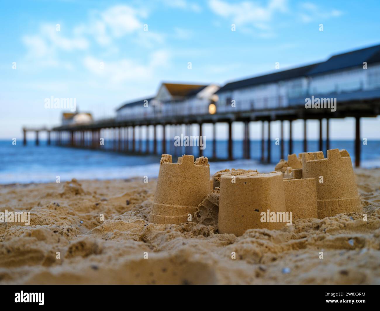 Southwold, Suffolk, Inghilterra - i resti di un castello di sabbia sulla spiaggia accanto all'iconico punto di riferimento del Suffolk del Southwold Pier. Foto Stock