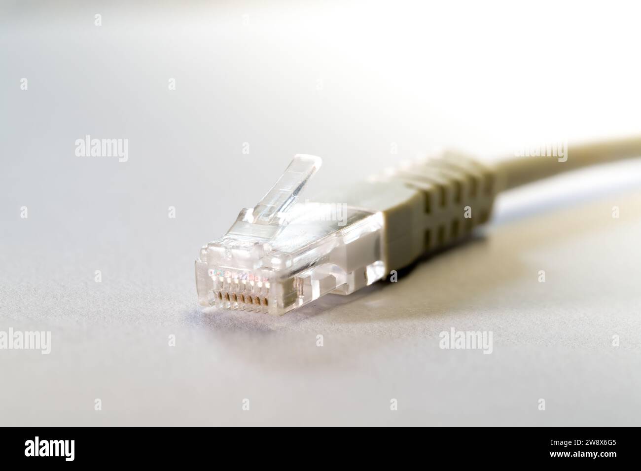 Primo piano di un cavo Ethernet RJ45 bianco su un tavolo bianco con spazio per la copia Foto Stock