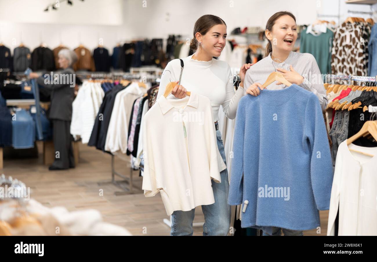 Due donne che scelgono un maglione comodo nel negozio di abbigliamento Foto Stock
