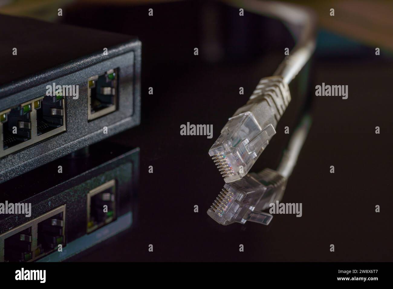 Primo piano di un cavo Ethernet RJ45 bianco su un tavolo nero con spazio per la copia Foto Stock