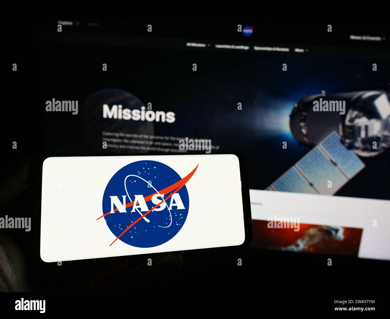 Persona in possesso di un cellulare con il logo dell'American National Aeronautics and Space Administration (NASA) davanti alla pagina web. Concentrarsi sul display del telefono. Foto Stock