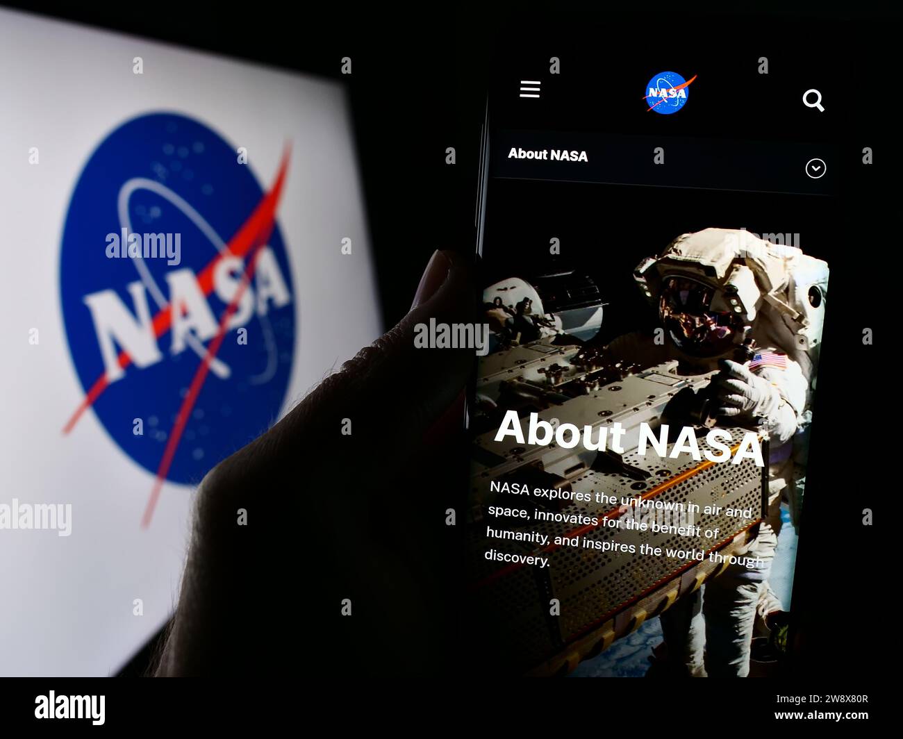 Persona in possesso di cellulare con pagina Web della NASA (National Aeronautics and Space Administration) con logo. Concentrarsi sul centro del display del telefono. Foto Stock