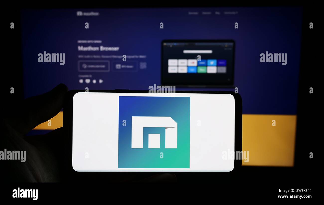 Persona che possiede uno smartphone con il logo della società di browser Web Maxthon davanti al sito Web. Concentrarsi sul display del telefono. Foto Stock