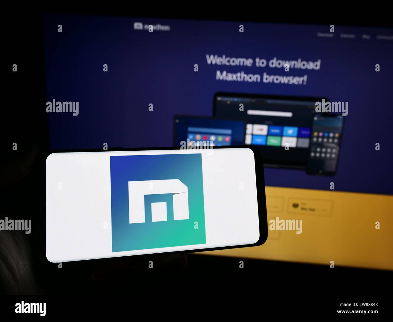 Persona che possiede un telefono cellulare con il logo della società di browser Web Maxthon davanti alla pagina Web aziendale. Concentrarsi sul display del telefono. Foto Stock