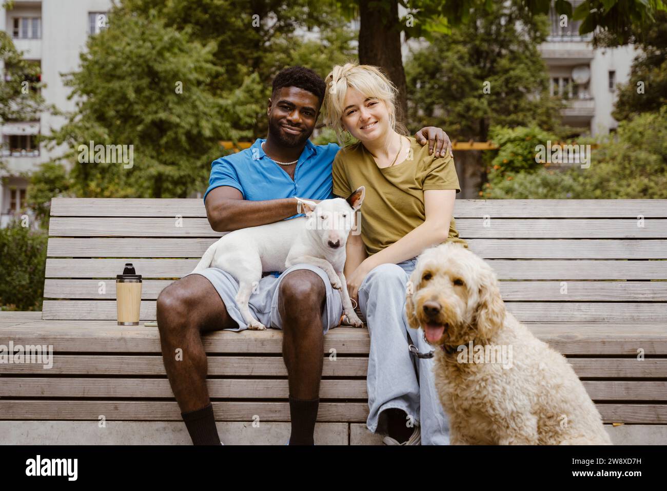 Ritratto di una sorridente coppia eterosessuale con cani nel parco pubblico Foto Stock