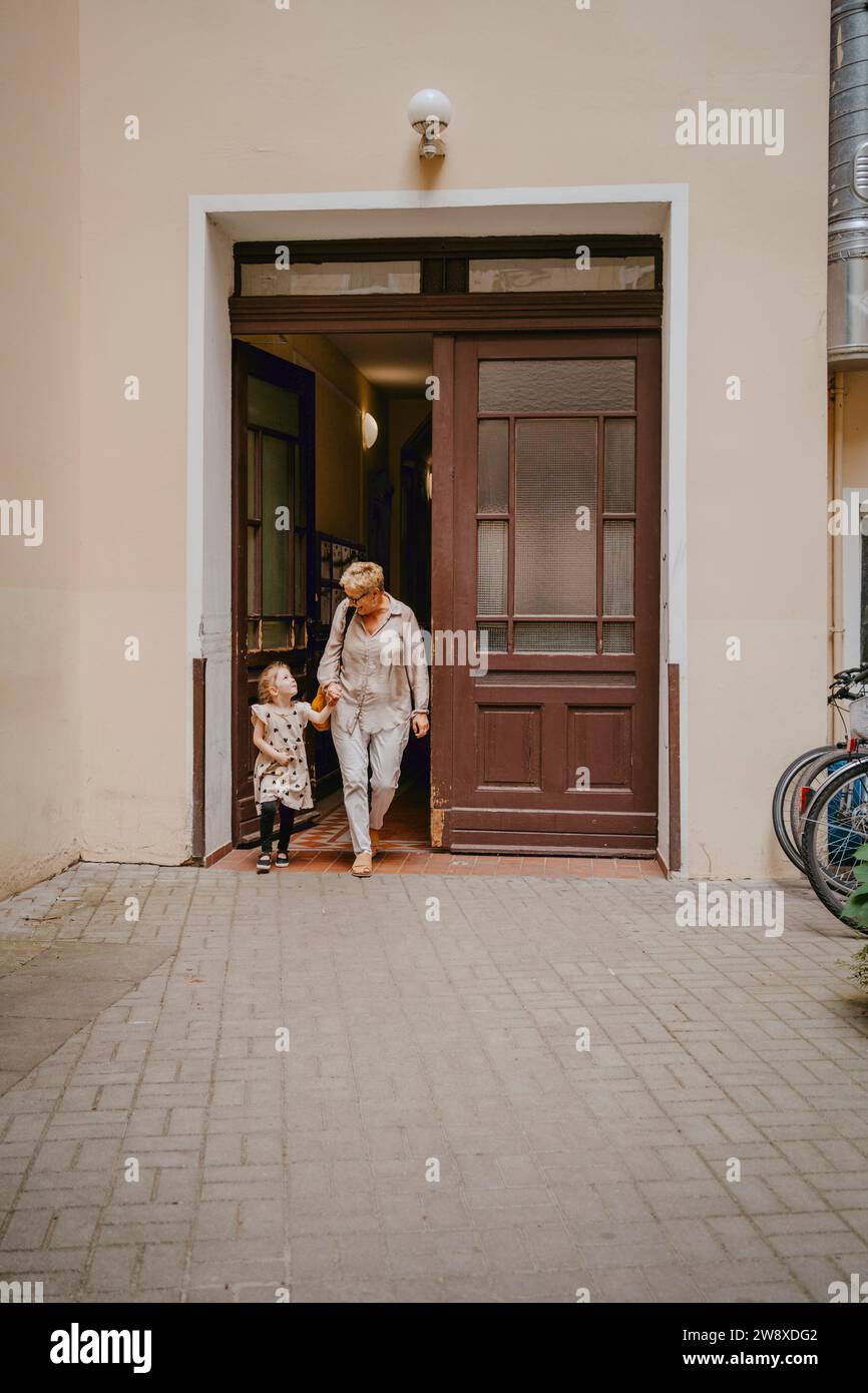 Nonna con nipote che esce dall'edificio Foto Stock
