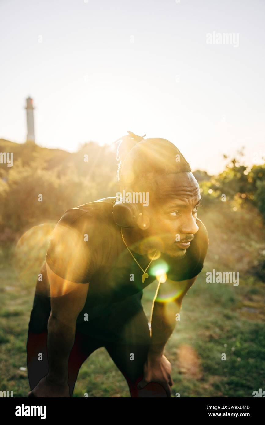 Uomo stanco che si piega con le mani sul ginocchio contro il cielo Foto Stock