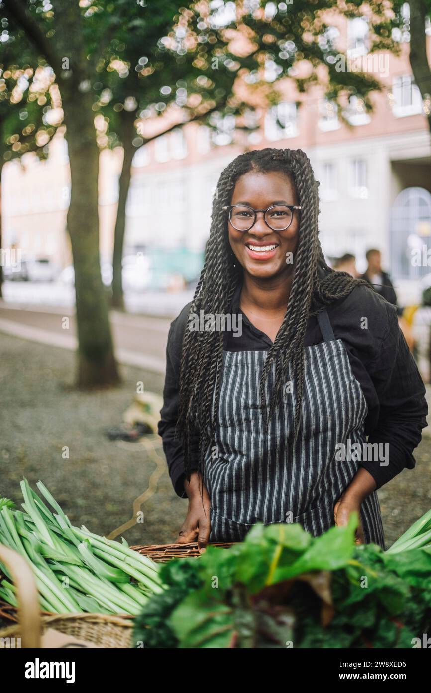 Ritratto di una donna felice con capelli intrecciati vicino al mercato vegetale Foto Stock