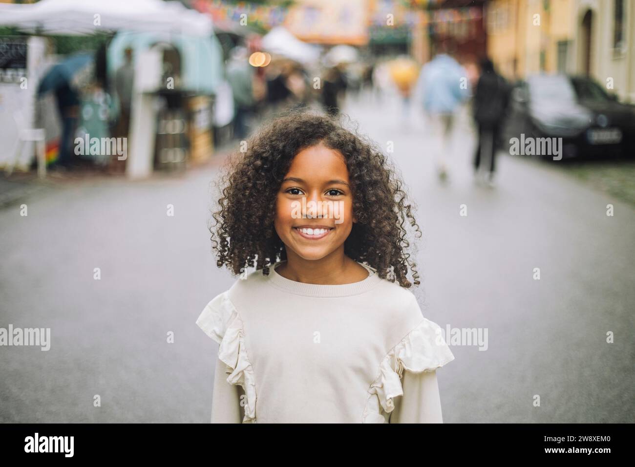 Ritratto di una ragazza sorridente con i capelli ricci al parco divertimenti Foto Stock