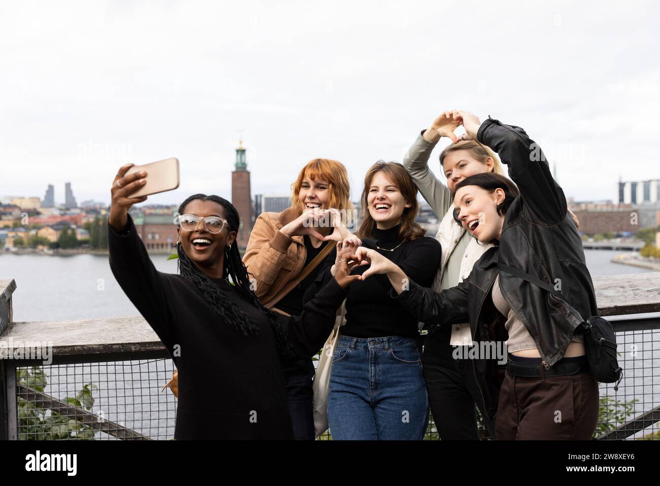 Allegri amici femminili che fanno gesti cardiaci mentre scattano selfie con lo smartphone in vacanza Foto Stock