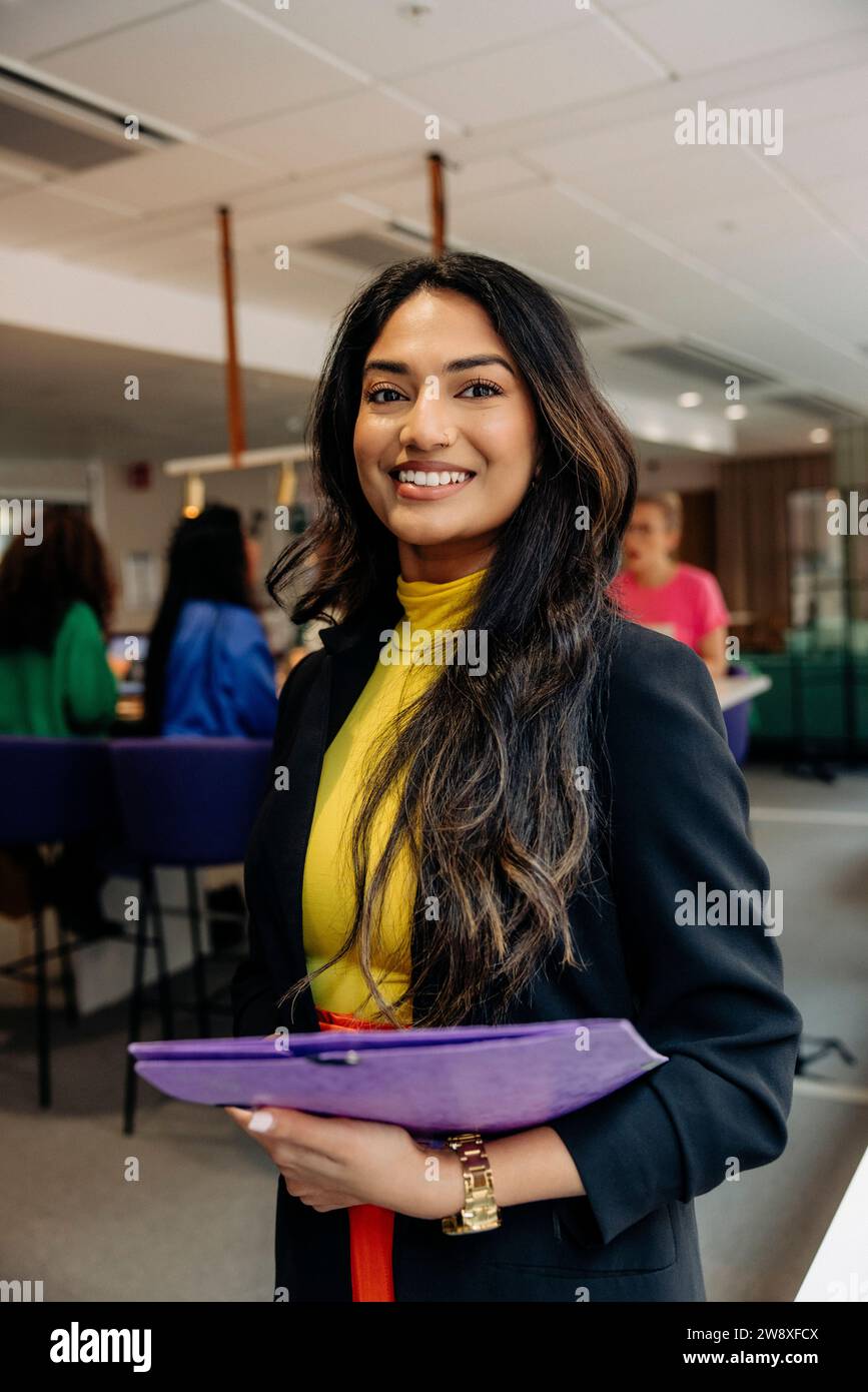 Una donna sicura che tiene il file mentre si trova in ufficio Foto Stock