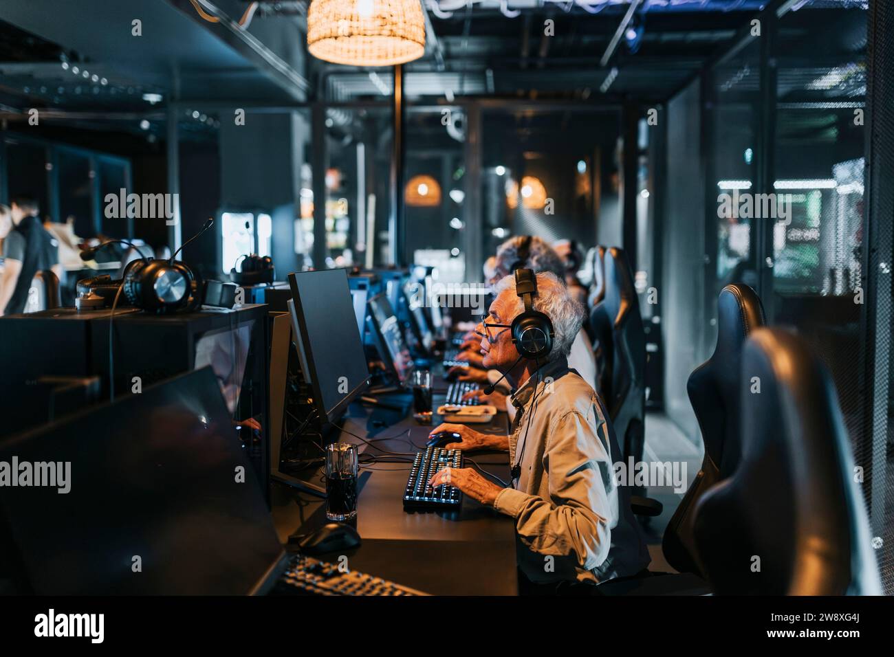 Uomo anziano che gioca a videogame per computer nella sala giochi durante il fine settimana Foto Stock