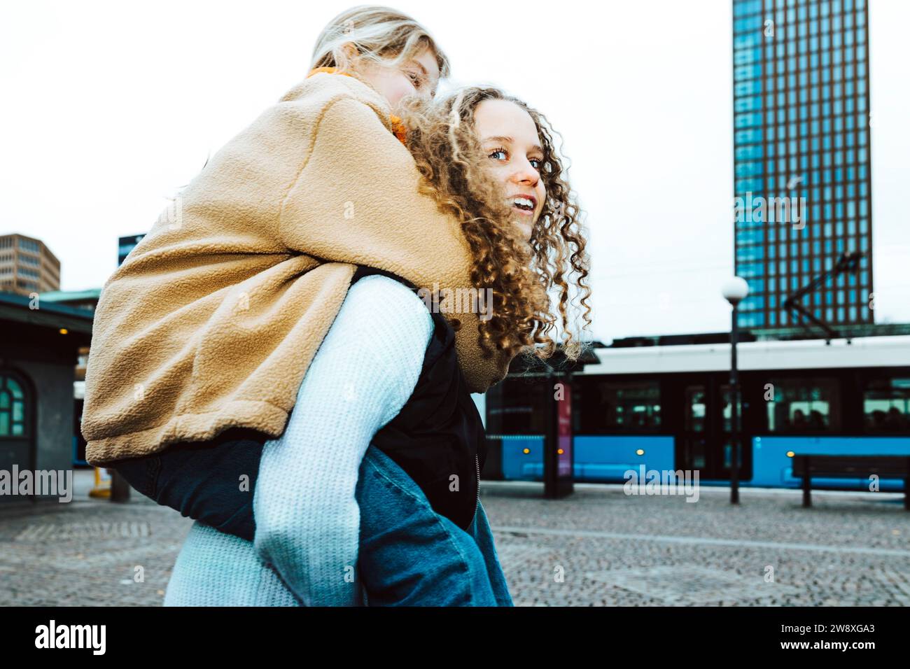 Ragazza che porta un'amica piggyback sul sentiero mentre si stende contro il cielo limpido Foto Stock