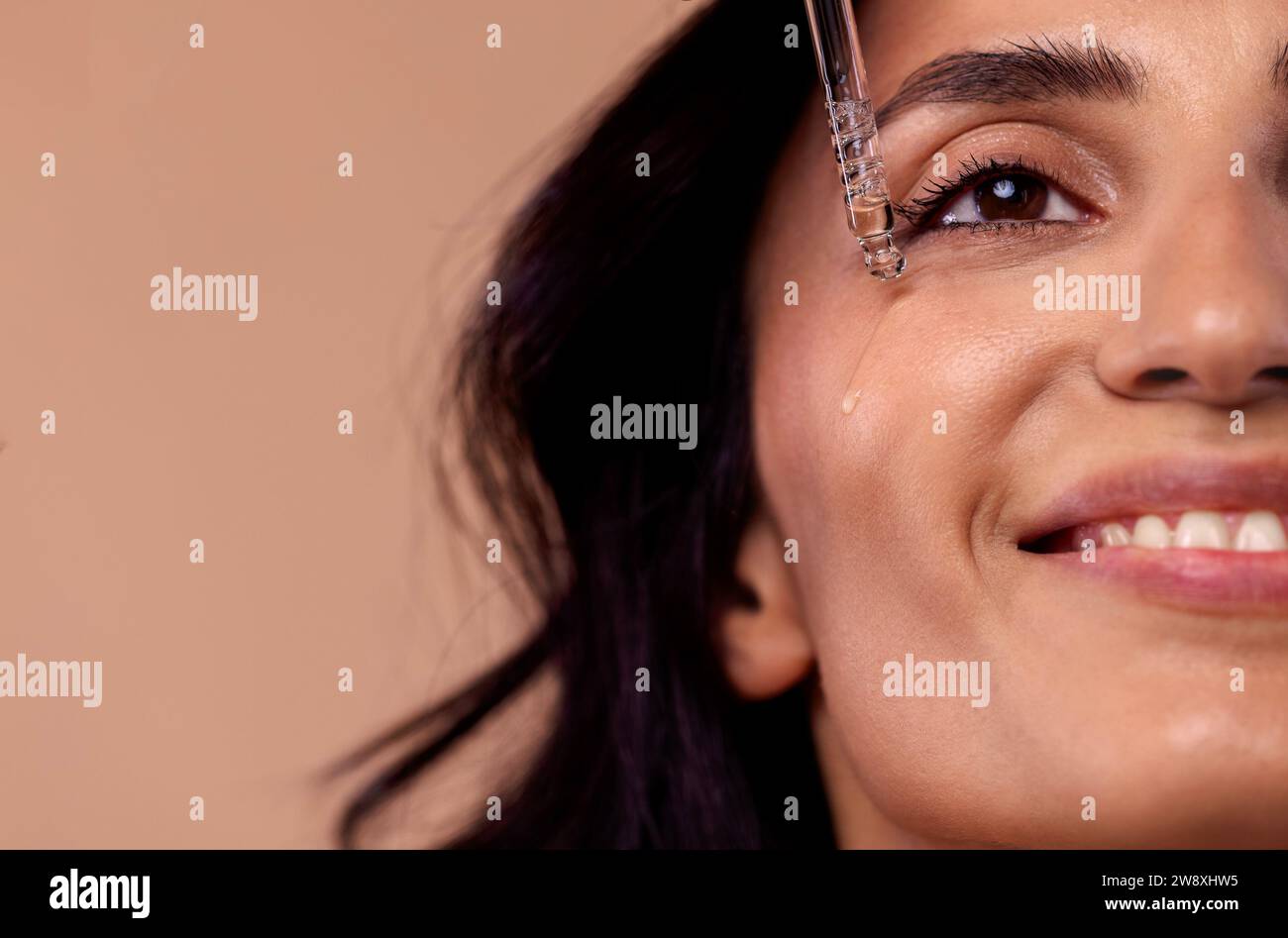 Primo piano di una donna affascinante che tiene una pipetta con siero rigenerante con acido ialuronico. Ragazza attraente con bella pelle sana e idratante Foto Stock