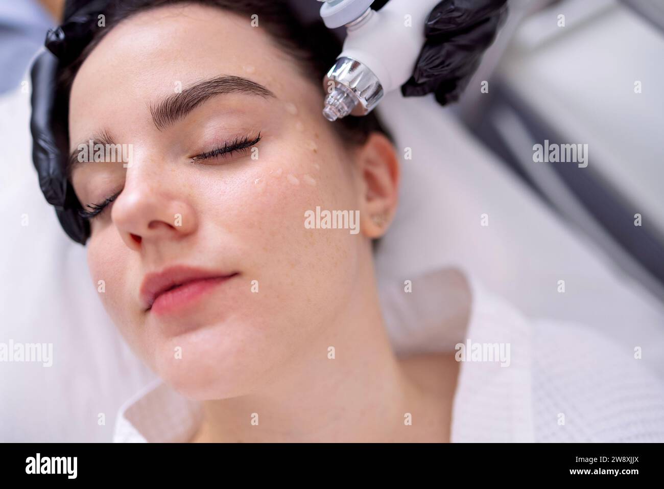 Donna caucasica che ottiene la procedura di peeling del viso in una clinica di bellezza, primo piano. Trattamento rigenerante con gas viso liquido. Idropulente per la pelle ad aria Foto Stock