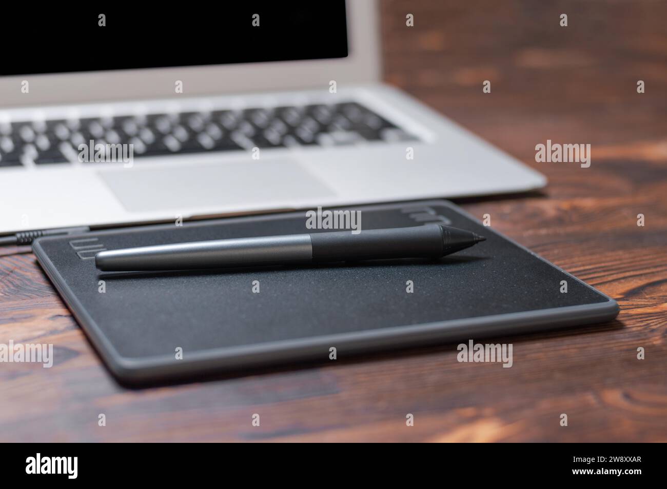Immagine di una tavoletta grafica, uno stilo e un laptop su un tavolo di legno. Ambiente di lavoro di design. Freelance. Ritocco. Concetto IT. Supporti misti Foto Stock
