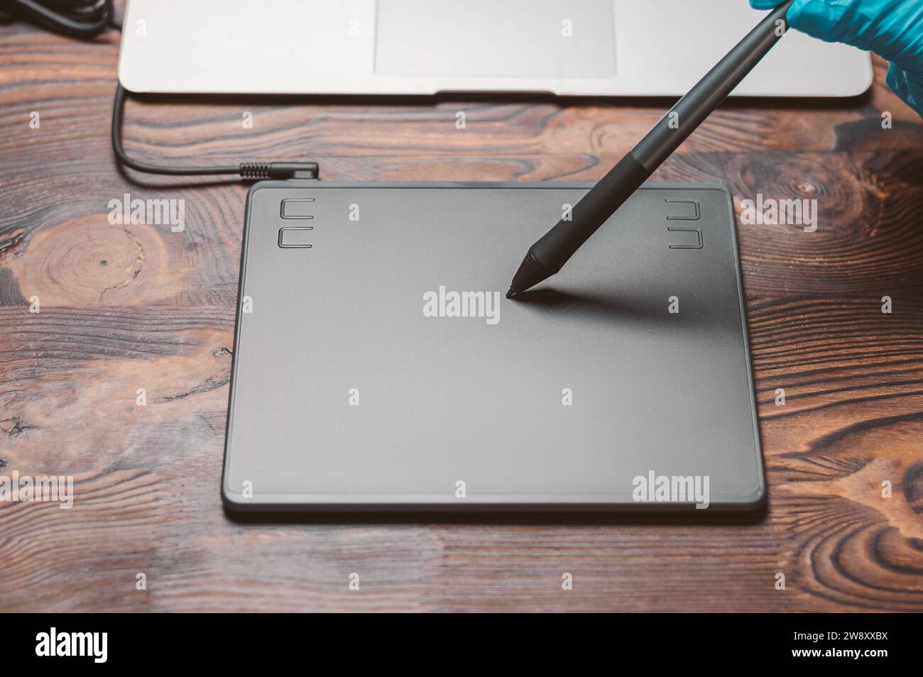 Immagine di una tavoletta grafica, uno stilo e un laptop su un tavolo di legno. Ambiente di lavoro di design. Freelance. Ritocco. Concetto IT. Supporti misti Foto Stock