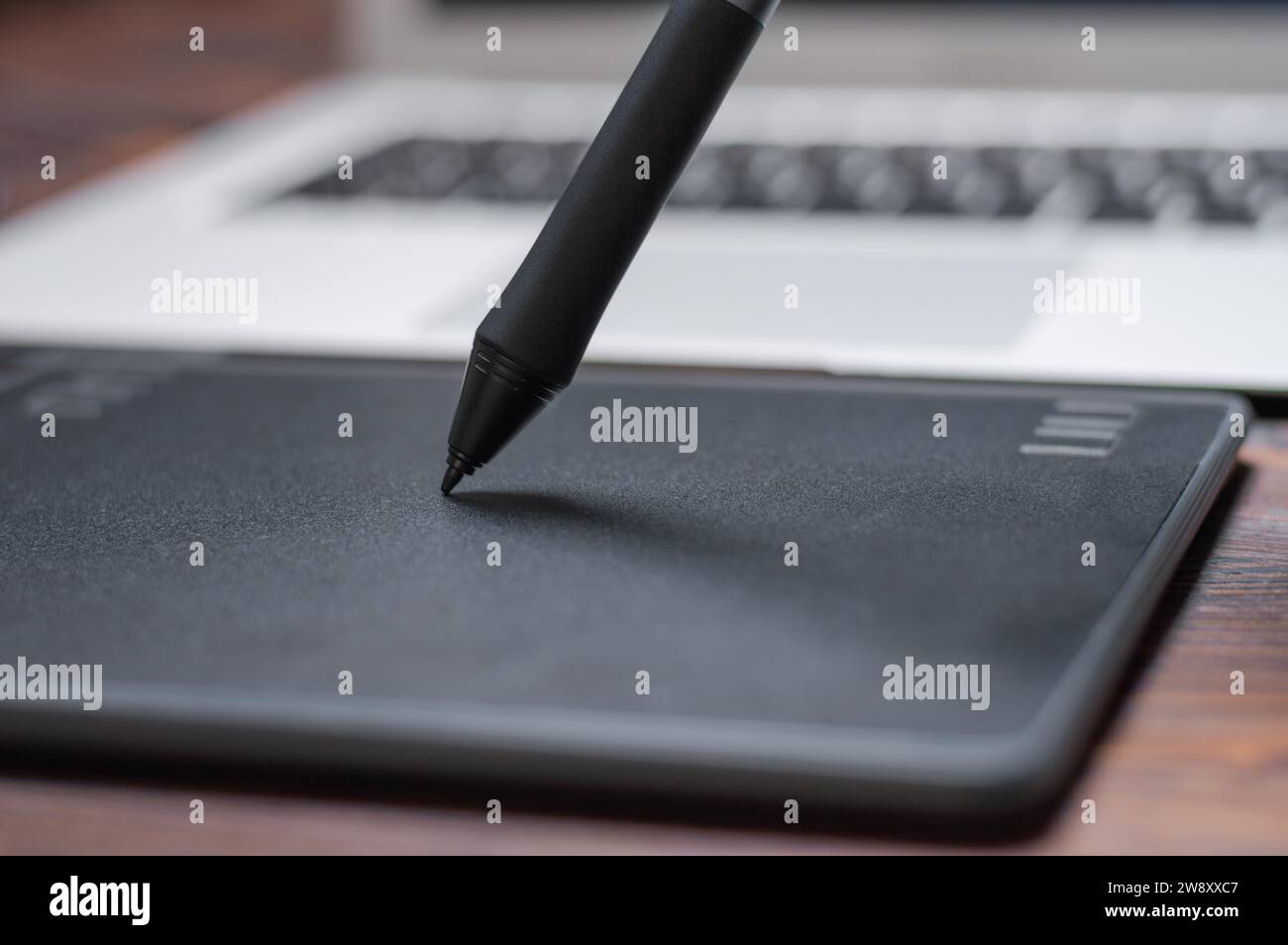 Immagine di una tavoletta grafica, uno stilo e un laptop su un tavolo di legno. Ambiente di lavoro di design. Freelance. Ritocco. Concetto IT. Supporti misti Foto Stock