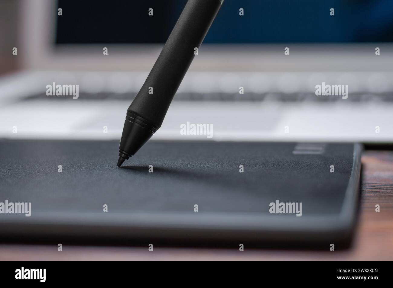 Immagine di una tavoletta grafica, uno stilo e un laptop su un tavolo di legno. Ambiente di lavoro di design. Freelance. Ritocco. Concetto IT. Supporti misti Foto Stock