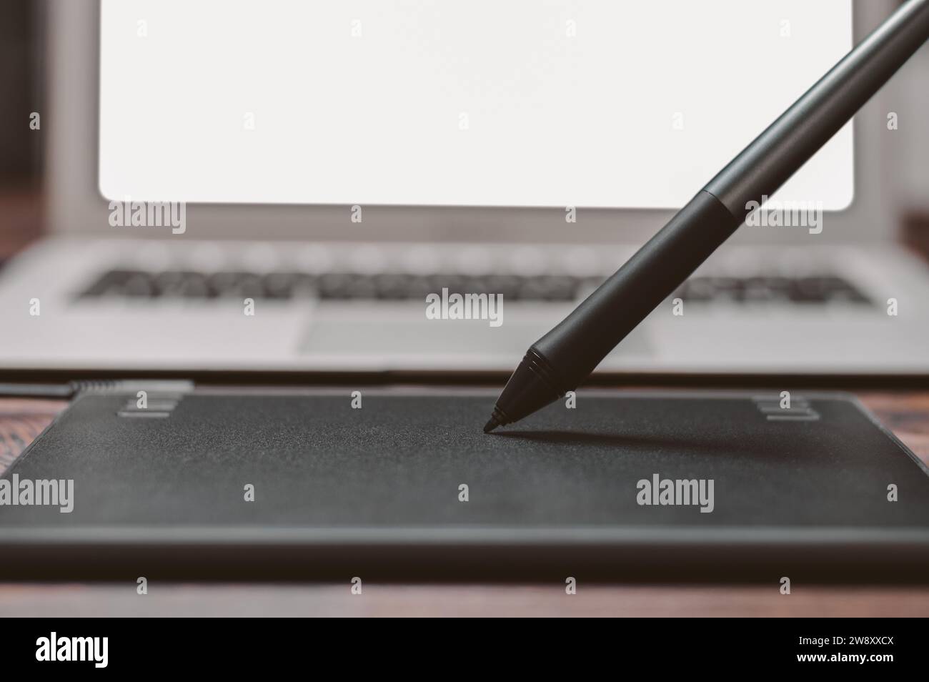 Immagine di una tavoletta grafica, uno stilo e un laptop su un tavolo di legno. Ambiente di lavoro di design. Freelance. Ritocco. Concetto IT. Supporti misti Foto Stock