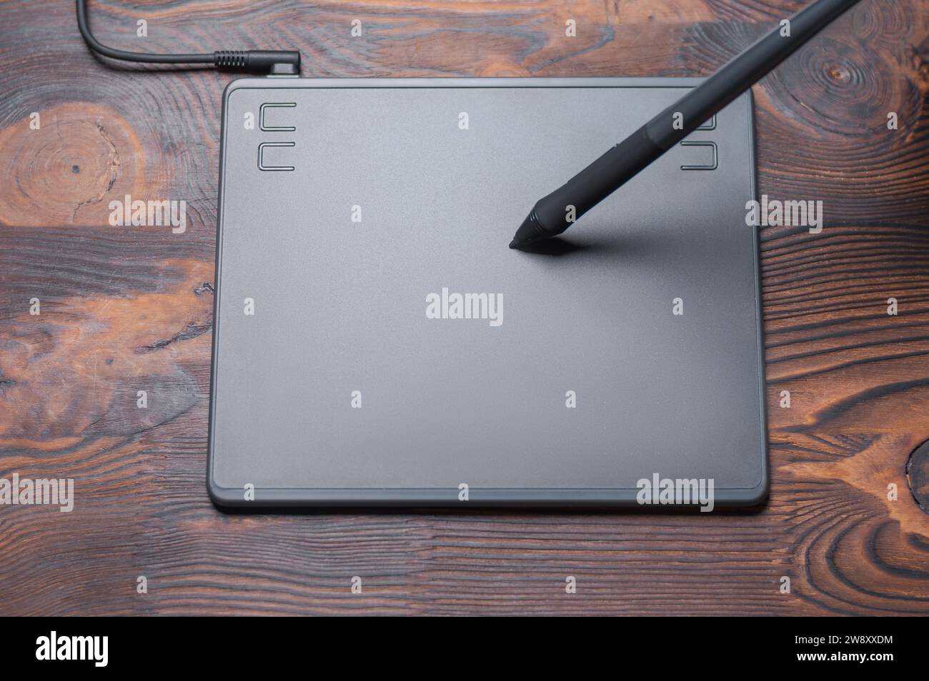 Immagine di una tavoletta grafica, uno stilo e un laptop su un tavolo di legno. Ambiente di lavoro di design. Freelance. Ritocco. Concetto IT. Supporti misti Foto Stock