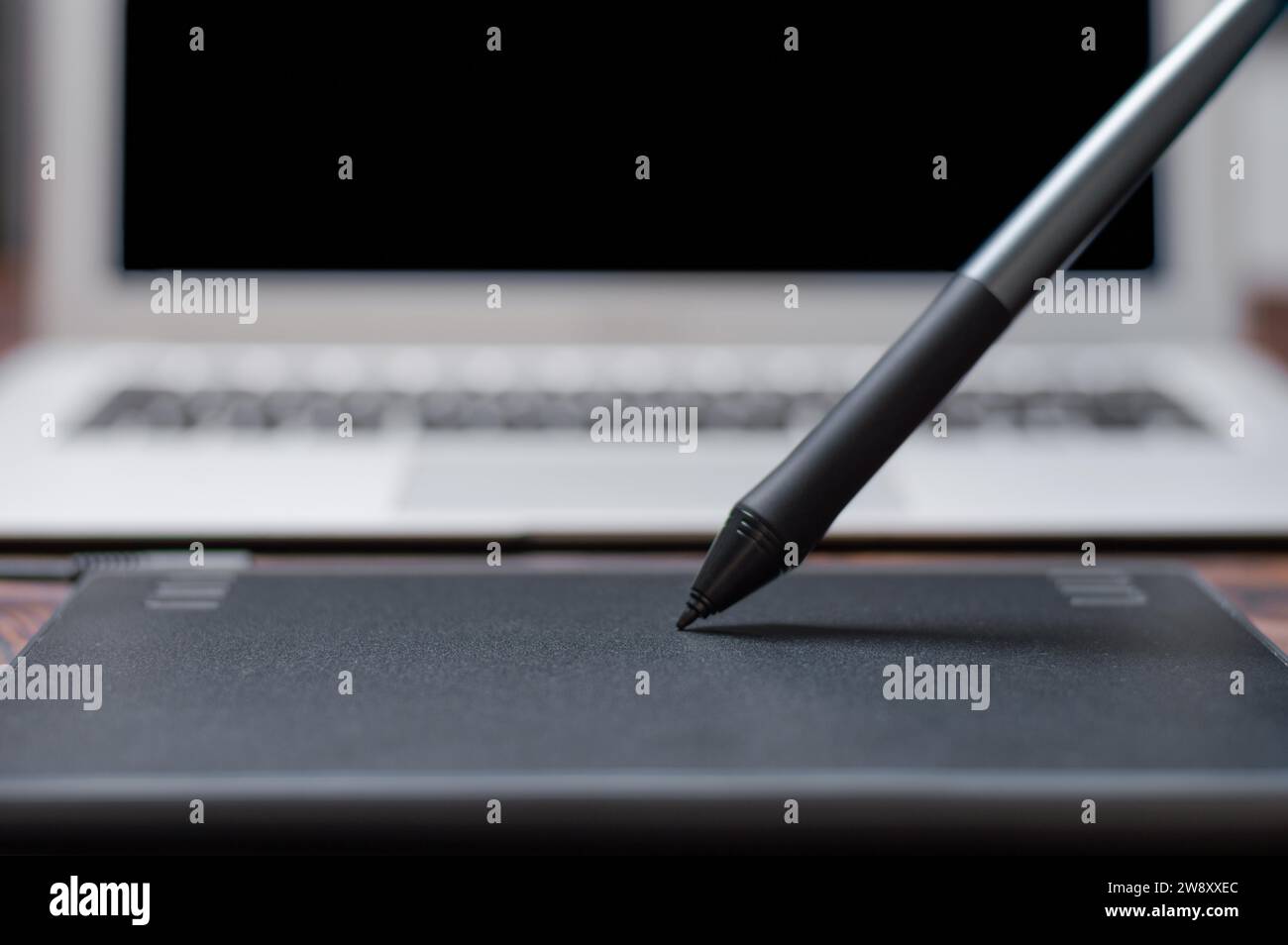 Immagine di una tavoletta grafica, uno stilo e un laptop su un tavolo di legno. Ambiente di lavoro di design. Freelance. Ritocco. Concetto IT. Supporti misti Foto Stock