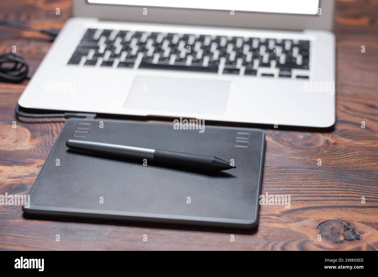 Immagine di una tavoletta grafica, uno stilo e un laptop su un tavolo di legno. Ambiente di lavoro di design. Freelance. Ritocco. Concetto IT. Supporti misti Foto Stock