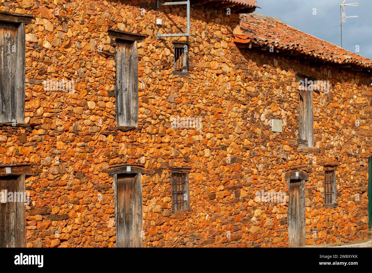 Case, finestre e facciate costruite con pietra calcarea rossa tipica della regione di la Maraguatería a Castilla y León, Spagna Foto Stock