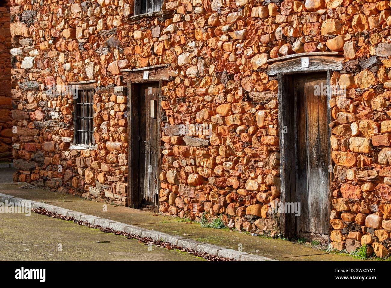 Case, finestre e facciate costruite con pietra calcarea rossa tipica della regione di la Maraguatería a Castilla y León, Spagna Foto Stock