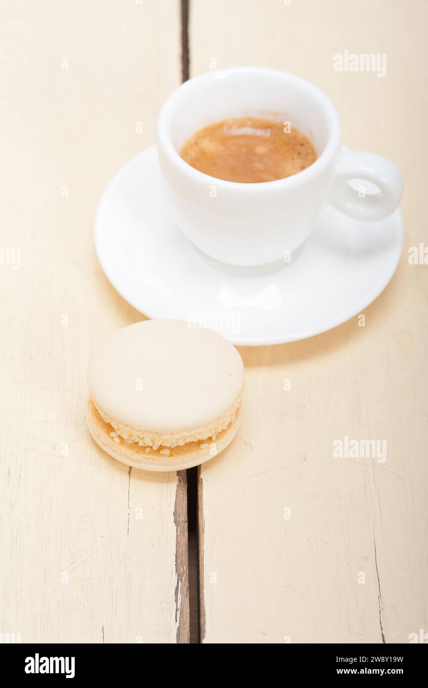 Macaron colorati con caffè espresso su un tavolo in legno bianco, fotografia gastronomica Foto Stock