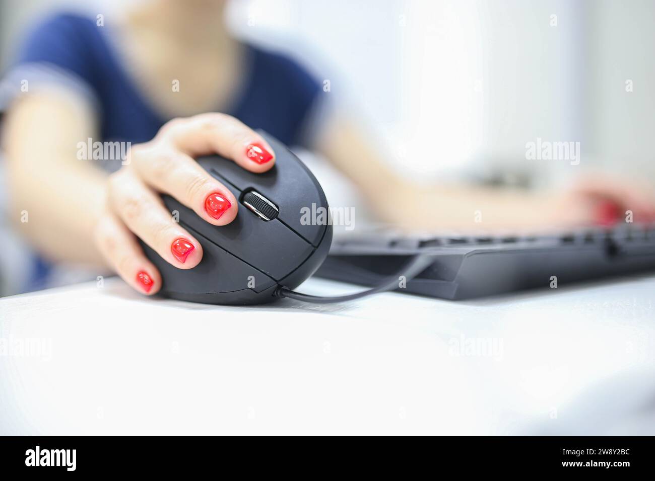 La mano della ragazza utilizza un joystick ergonomico verticale di un mouse del computer. lavoro al computer Foto Stock