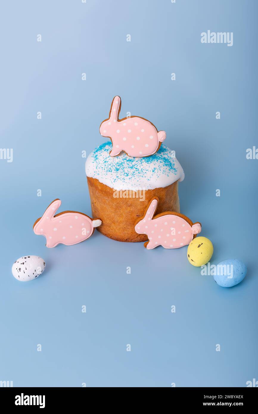 Tre graziosi pani di zenzero rosa a forma di coniglio sulla torta pasquale e uova decorative Foto Stock