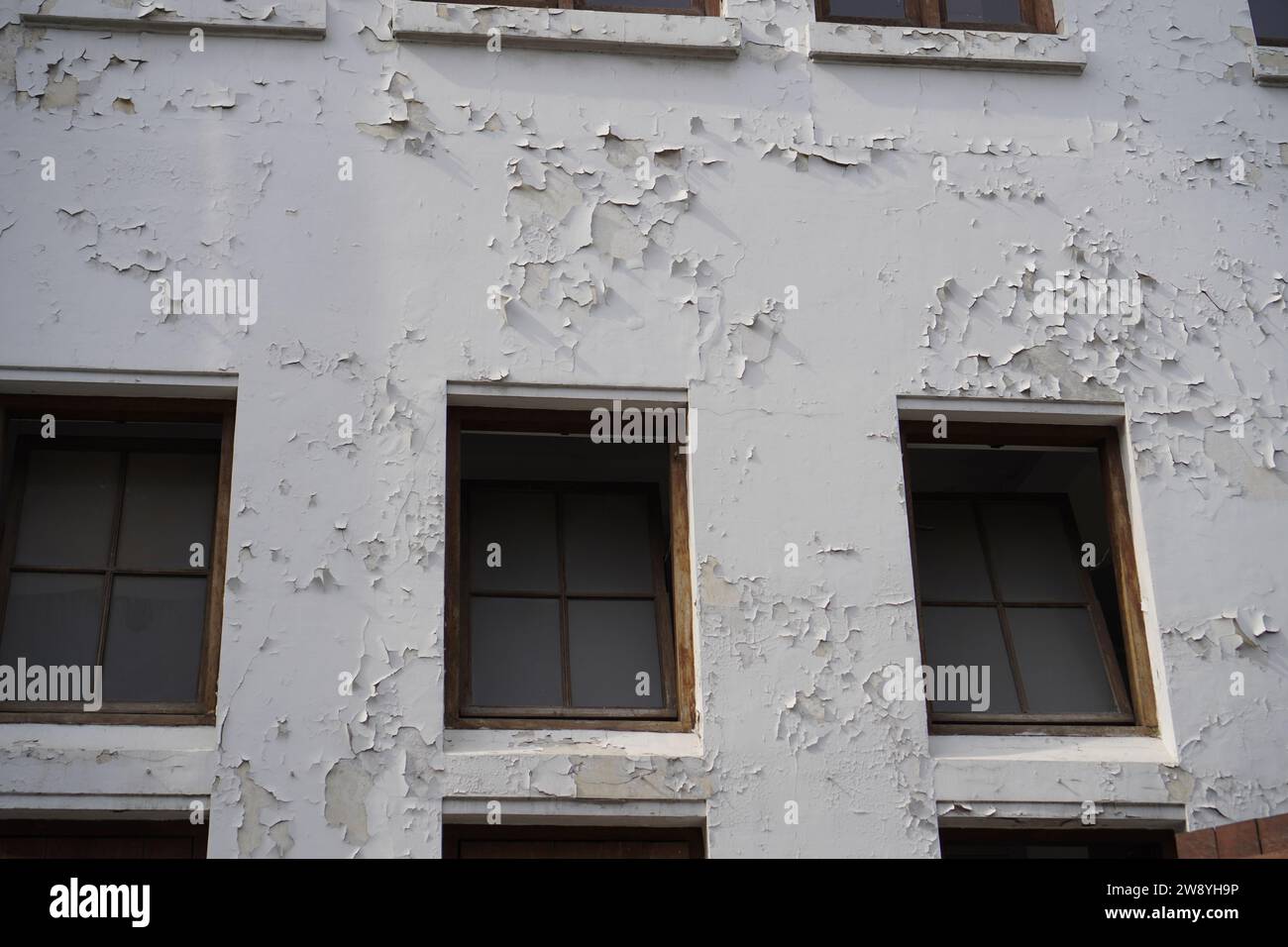 sembra logoro dalle finestre dell'edificio con la vernice delle pareti che si staccava Foto Stock