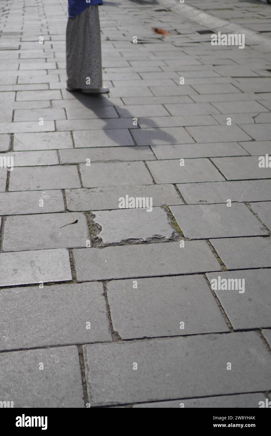 vista ravvicinata delle ombre pedonali su una strada in mattoni Foto Stock