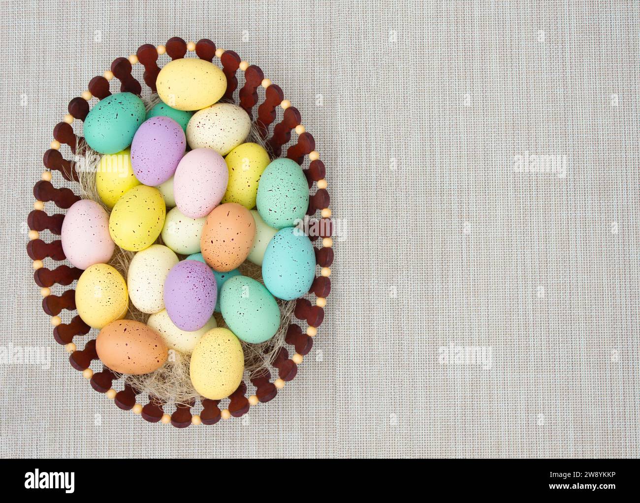 Uova di Pasqua colorate nel cesto di legno sullo sfondo ruvido. Copia spazio Foto Stock