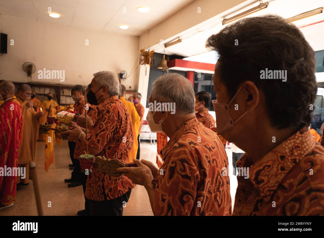 Bandung, Indonesia - 8 gennaio 2022: Il vecchio porta le offerte all'altare mentre prega con i monaci all'interno del tempio del Buddha Foto Stock