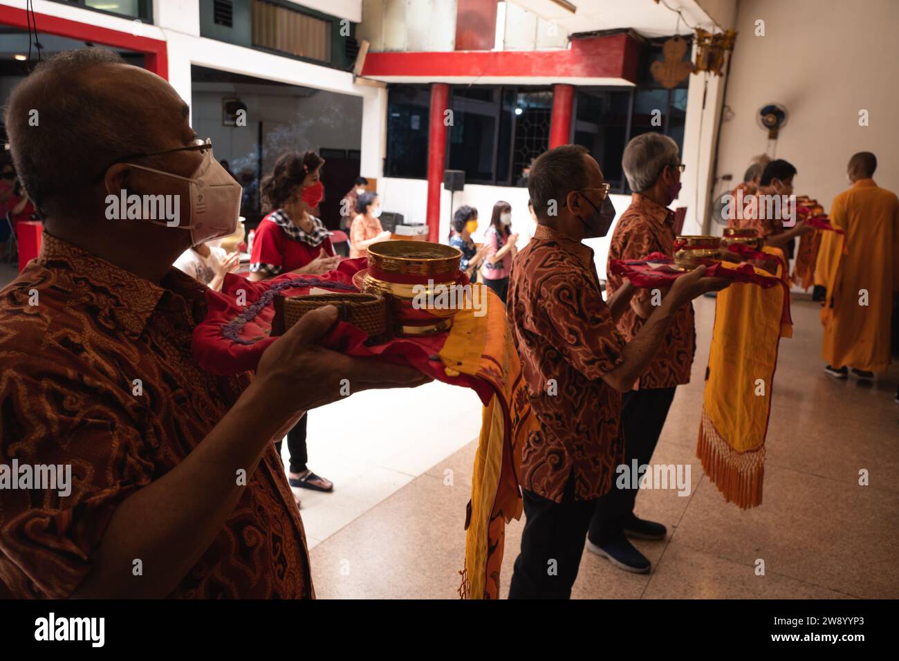 Bandung, Indonesia - 8 gennaio 2022: Il vecchio porta le offerte all'altare mentre prega con i monaci all'interno del tempio del Buddha Foto Stock