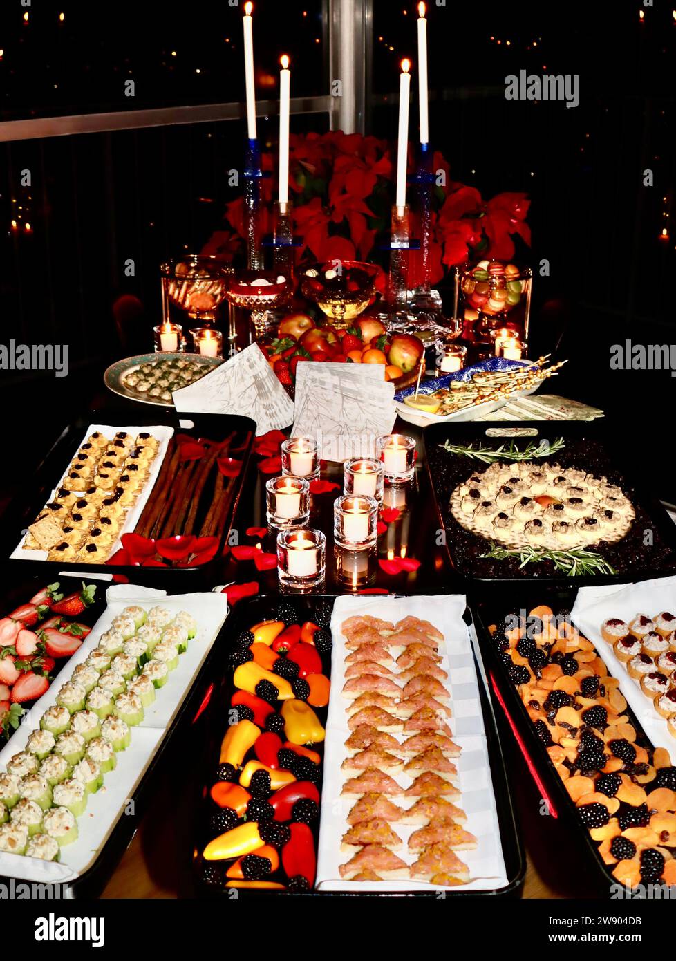 Selezione di antipasti natalizi e decorazioni sul tavolo con candele e petali di rosa. Foto Stock