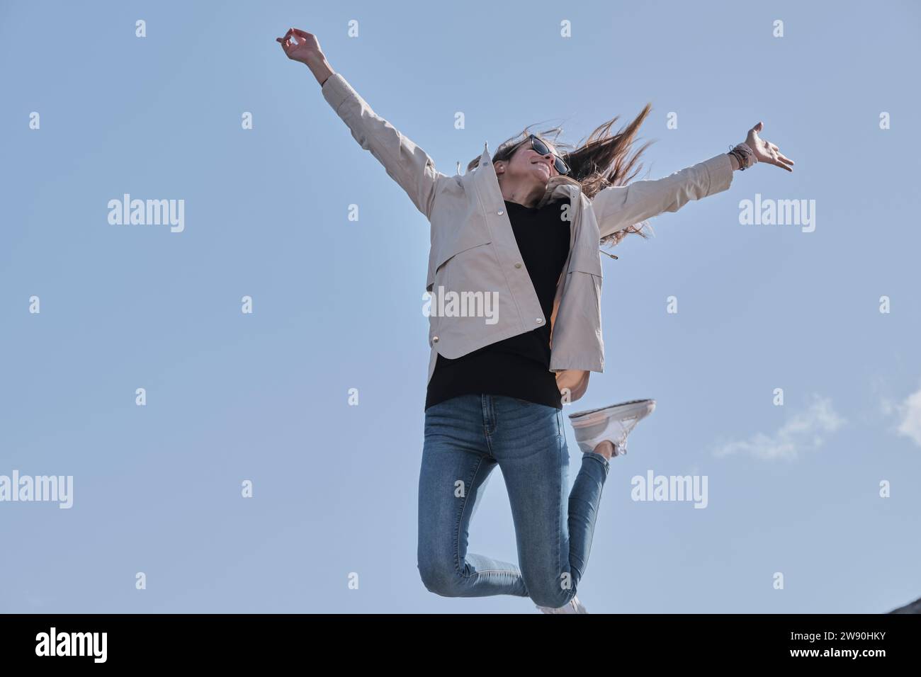 Una ragazza caucasica salta molto in alto per celebrare un risultato esprimendo la sua felicità. Foto Stock