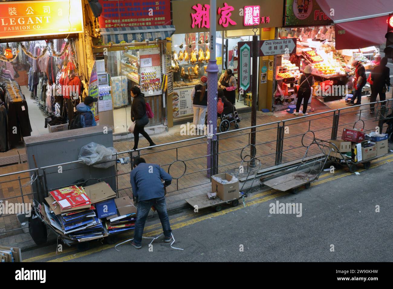Uomo che raccoglie scatole di cartone fuori dal negozio in 'Seafood Street' - Des Voeux Road, Western, Hong Kong, Cina Foto Stock
