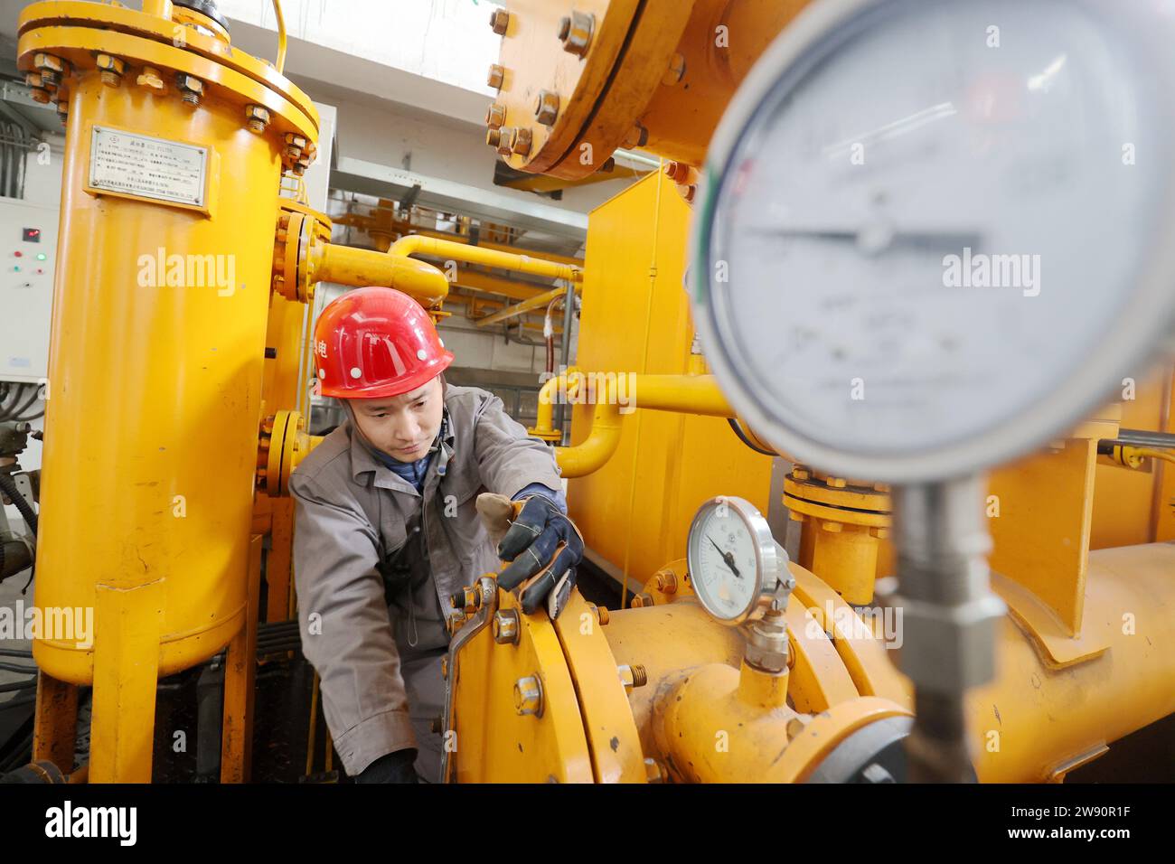 Pechino, provincia cinese di Zhejiang. 23 dicembre 2023. Un membro dello staff di una società di fornitura di calore controlla le attrezzature nella Leidian Township della contea di Deqing, città di Huzhou, provincia dello Zhejiang della Cina orientale, 23 dicembre 2023. Sono state adottate contromisure per prevenire o alleviare gli impatti causati da nevicate estese e altre condizioni di congelamento. Crediti: Xie Shangguo/Xinhua/Alamy Live News Foto Stock
