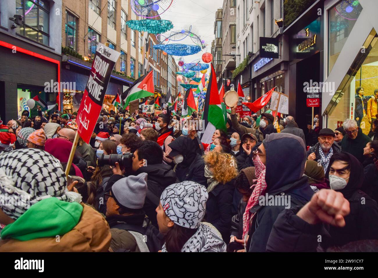 Londra, Regno Unito. 23 dicembre 2023. Manifestanti fuori dal negozio Puma in Carnaby Street. I manifestanti pro-Palestina hanno marciato attraverso il quartiere dello shopping di Londra prima di Natale, chiedendo un cessate il fuoco. Credito: Vuk Valcic/Alamy Live News Foto Stock