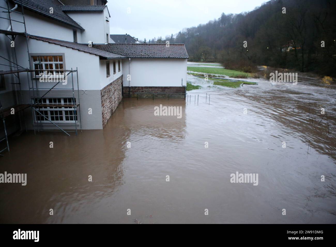 Bad Karlshafen, Germania. 23 dicembre 2023. Il fiume Diemel ha fatto irruzione sulle sue rive. La pioggia persistente sta aggravando ulteriormente la situazione delle inondazioni in Assia. Secondo l’Agenzia statale dell’Assia per la conservazione della natura, l’ambiente e la geologia (HLNUG), anche il bacino idrografico del Diemel è particolarmente interessato. Crediti: Stefan Rampfel/dpa/Alamy Live News Foto Stock