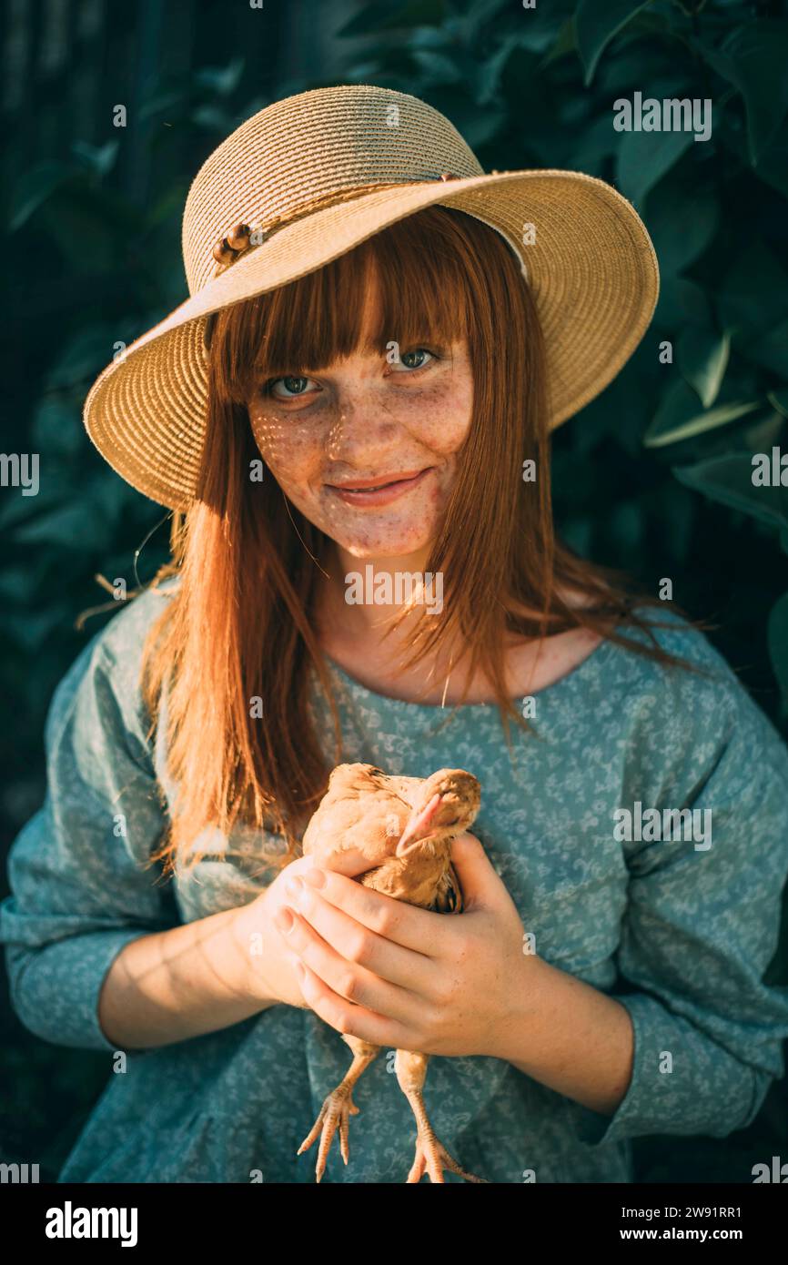 Giovane donna rossa con lentiggini che regge il pollo Foto Stock