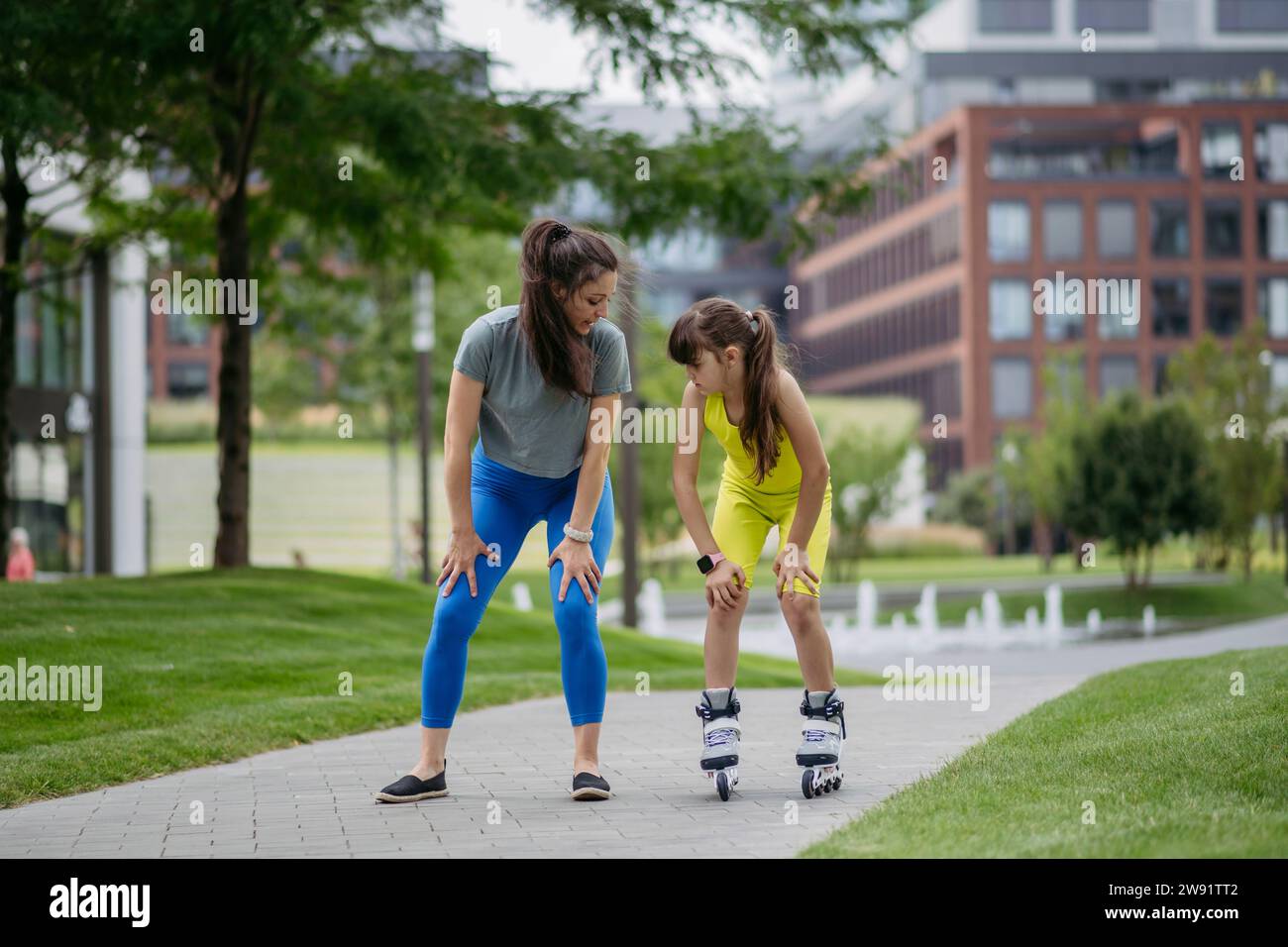 Madre insegna a sua figlia a pattinare a rotelle in città Foto Stock
