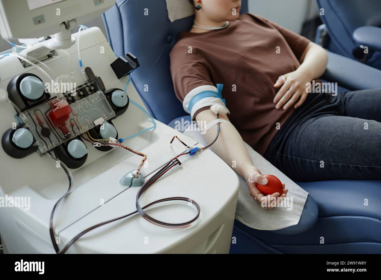 Giovane donna sdraiata sul divano con la palla in mano al centro di donazione del sangue Foto Stock