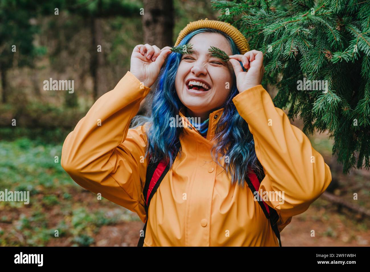 Donna felice che tiene i ramoscelli sulle sopracciglia nella foresta Foto Stock