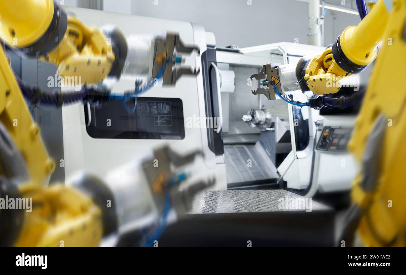 Bracci robotici gialli con macchinari in fabbrica Foto Stock