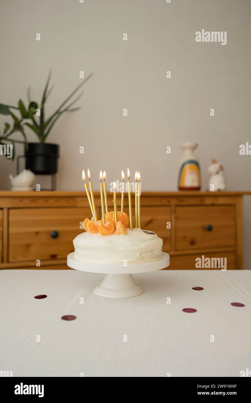 Torta di compleanno con fette di mandarini e candele sul tavolo Foto Stock