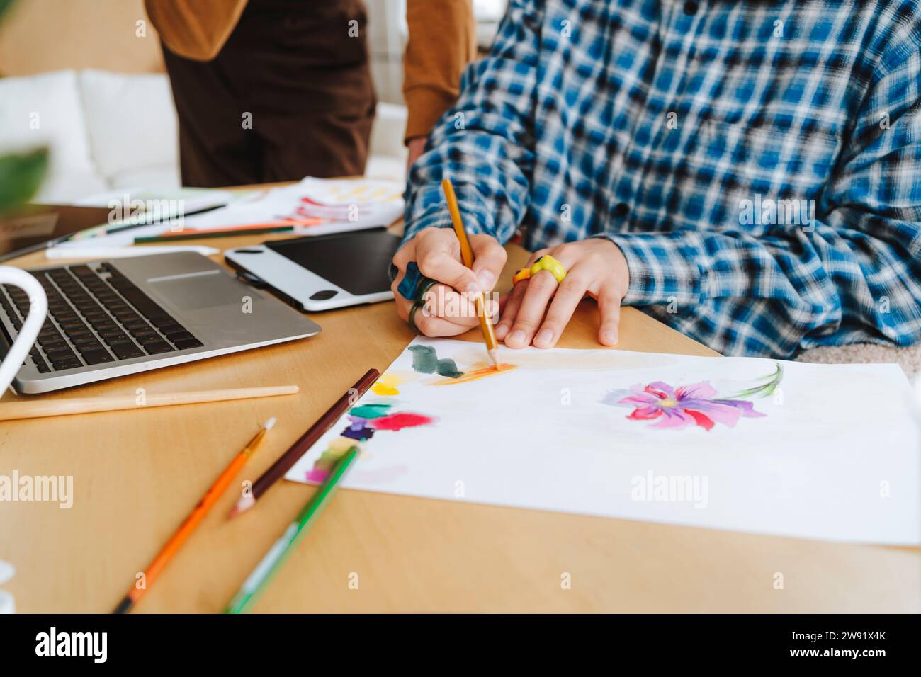 Giovane designer grafico che colora su carta alla scrivania in ufficio Foto Stock